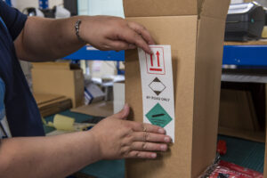 Warehouse operative sticking a dangerous goods sticker on a shipment.