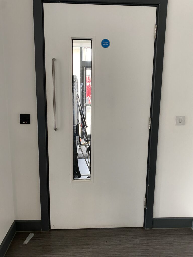 White fire door in a corridor leading onto stairwell