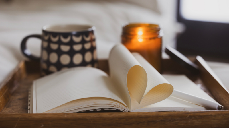 A burning candle on a tray with a book