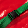 Close up of green strap and black plastic buckle on emergency evacuation sledge against a red background