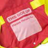 Close up of red and yellow emergency evacuation sheet with a patch label stating THIS SIDE UP and Please Return To