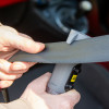 Close-up of aa emergency car torch window hammer belt cutter cutting through a black seatbelt in action
