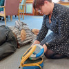 Person kneeling on floor removing heartsine samaritan pad 350p defibrillator from its yellow case