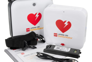 A white defibrillator and carry case with a battery and charging cable