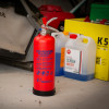 p50 2kg powder extinguisher standing upright on a workshop floor with containers and tools in the background