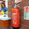 p50 2ltr water mist fire extinguisher mounted on a brick wall with a carer serving drinks in the background