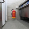 p50 wet chemical extinguisher mounted on kitchen wall with grey tiles and stainless steel appliances nearby