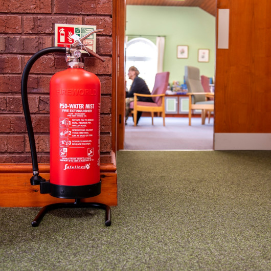 P50 water mist fire extinguisher on a stand by a doorway