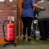 p50 6ltr water mist fire extinguisher on stand next to a carer assisting a patient with a walking aid