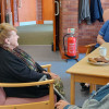 p50 6ltr water mist fire extinguisher standing on a metal stand against a brick wall in a room with people sitting at a table