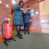 p50 6ltr water mist fire extinguisher on stand with two people discussing a brochure nearby