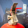 britannia p50 fire extinguisher wall bracket shown fixed to a blue wall with a fire extinguisher valve attached