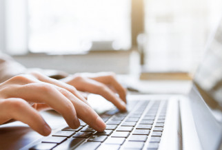 hand typing a blog on a laptop keyboard