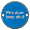 Front view of a fire door keep shut metal sign showing white text on a round blue background