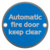 Round metal sign with text automatic fire door keep clear on a blue background front view