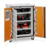An open metal cabinet with three shelves holding STIHL batteries and chargers, all plugged into internal sockets, with a safety sheet on the left door.