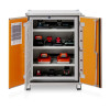 A metal cabinet with open orange doors showing multiple shelves of STIHL power tool batteries and chargers neatly arranged and connected.