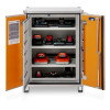 Metal cabinet with orange doors open, showing three shelves of STIHL battery chargers and batteries plugged in for charging