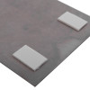 Close up of self adhesive wall mounting kit showing two white foam pads attached to a grey surface