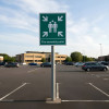 Csapalpl Aluminium Fire Assembly Point Sign Large mounted on a metal pole in a car park under a partly cloudy sky