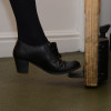 Foot wearing black shoe pressing foot operated door opener decamed on wooden door base