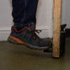 Foot wearing sturdy shoe using foot operated door opener decamed attached to wooden door bottom edge