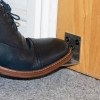 Foot pressing on decamed stainless steel foot operated door opener fixed to wooden door at floor level