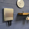 henry wolfe fire blanket cover installed on a blue painted brick wall below a wall clock and beside a wood shelf with a mug hanging