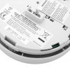 Close-up of the back of a smoke alarm displaying printed product labels, warnings, and a battery or connector compartment.
