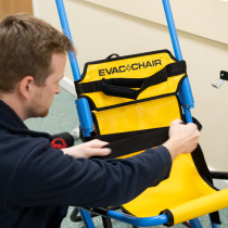 Engineer inspecting the yellow and blue Evacchair during an evacchair servicing session
