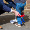 Person adjusting the paraid child carrier harness on a child standing outside against a brick wall