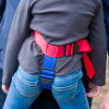 paraid child carrier harness shown fitted and ready with red and blue straps on child wearing jeans and a grey top