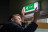 Man testing illuminated emergency lighting exit sign on wall titled Emergency Lighting Testing
