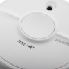 Closeup of the button on a FireAngel battery optical smoke alarm showing the test label and sensor hole