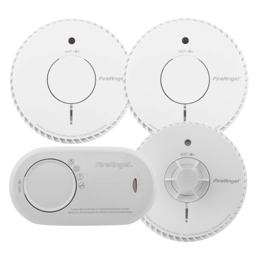 Four FireAngel alarms including two circular smoke alarms and a heat alarm with test/silence buttons and an oval carbon monoxide alarm with multilingual labelling.