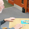 dorgard fire door retainer shown installed on a wooden door with a man doing a puzzle at a table nearby