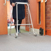 Person walking through open door with frame and dorgard fire door retainer fixed to skirting board on right side