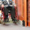 dorgard fire door retainer fixed to door with wheelchair passing through an open door in a hallway