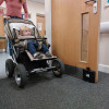Child in pushchair passing through a doorway held open by the dorgard smartsound door retainer