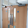 Pair of freedor smartsound door closers fitted on a set of wooden double doors with glass panels