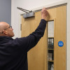 Man inspecting a fire door in an office setting as part of a fire door inspection