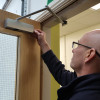 Person inspecting the metal mechanism on a fire door inside a warehouse environment