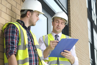 Two men in hard hats and high visibility vests reviewing documents on a clipboard for Fire Risk Assessment Information