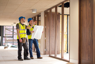 Two men in hard hats reviewing building plans inside a construction site for Fire Strategy