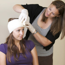 a woman practicing putting a bandage on a persons head