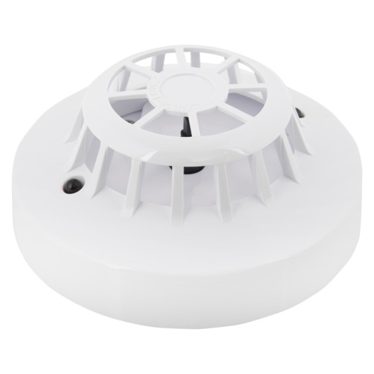angled close-up of an apollo discovery heat detector showing its round white casing and vented top design