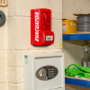 Red Fmcevasmbgc Evacuator Sitemaster Call Point Site Alarm mounted on a beige cinder block wall in a workshop setting