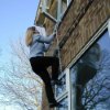 Person climbing down saf escape ladder attached outside a brick building during daylight