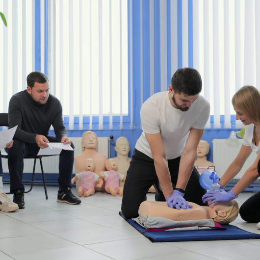 Group practising CPR on training mannequin during Frtotaed First Response Training Aed And Cpr Course Group Cpr Session
