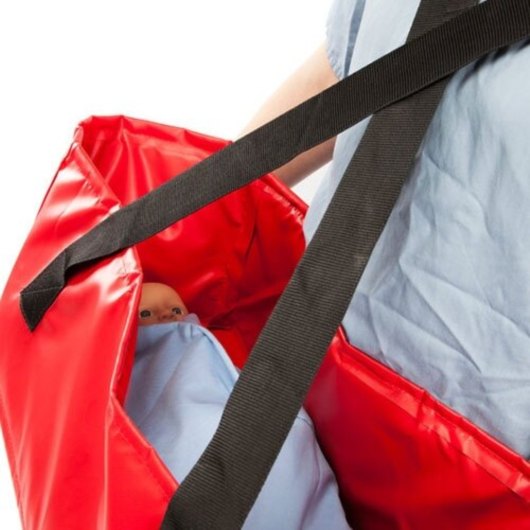 Close up of the red material and black straps of the buscot babevac evacuation cot with a small doll inside wrapped in blue fabric